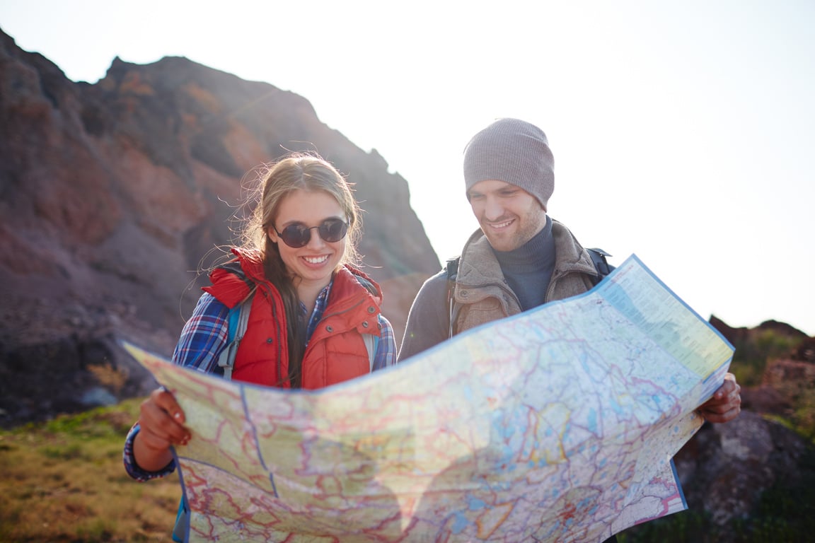 Couple on an adventure looking at a map, representing travel planning and exploration for your ultimate travel guide.